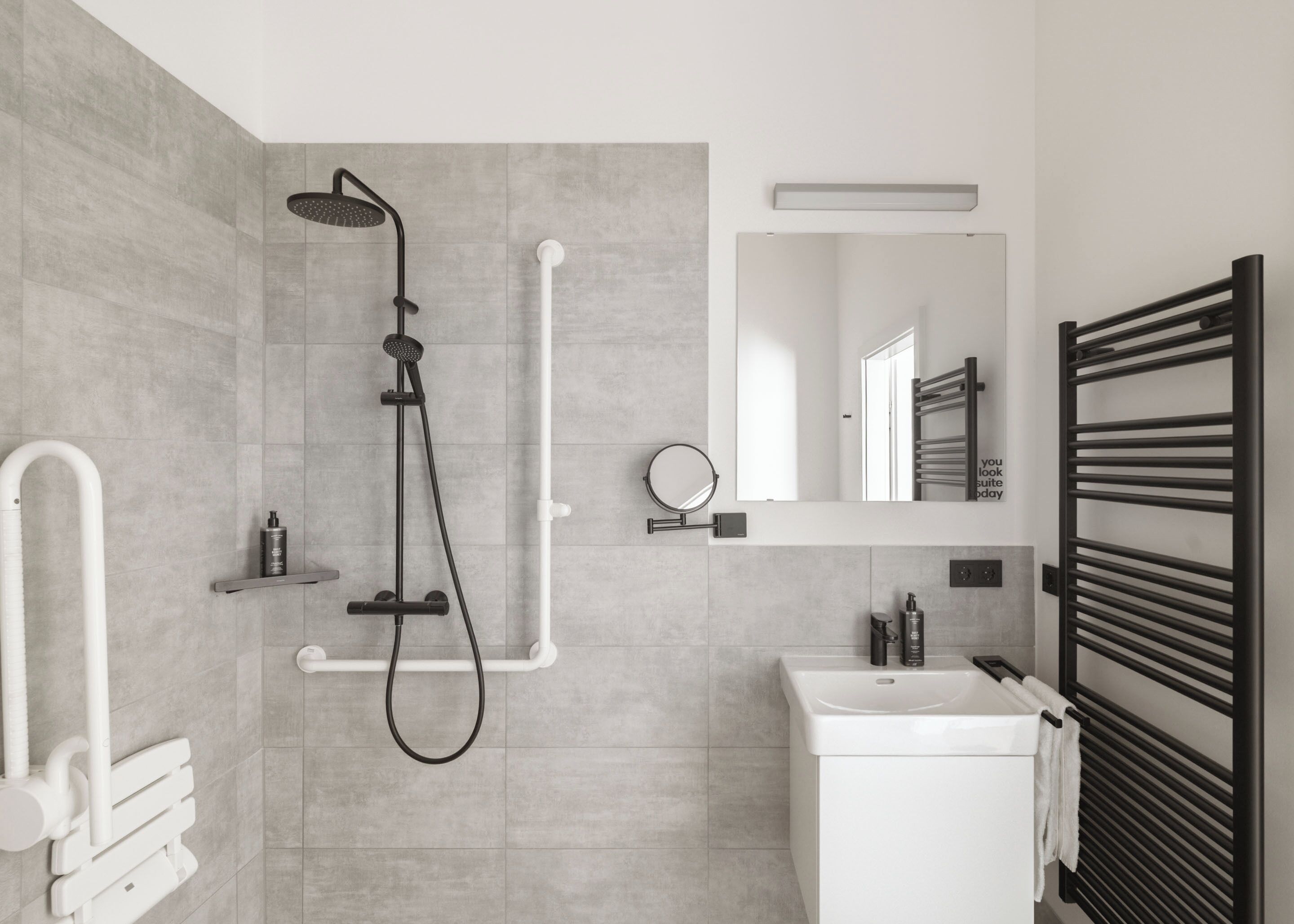A modern bathroom with a shower, sink, and towel rack.