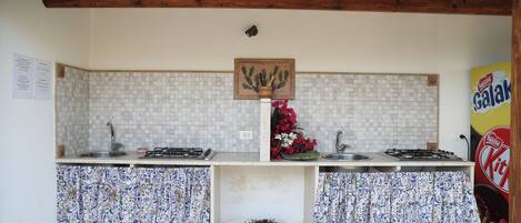Una cocina con dos fregaderos, techo de madera, salpicadero de azulejos y cortinas estampadas.