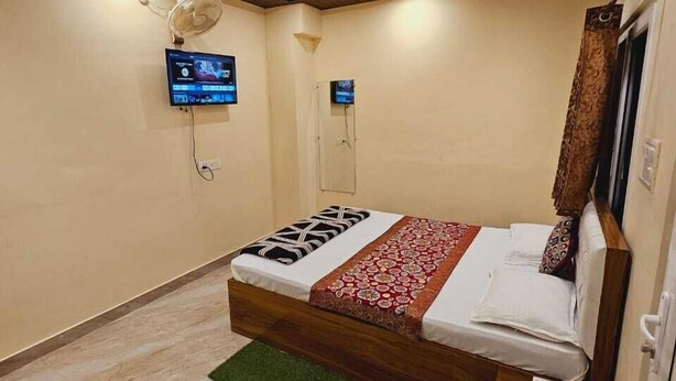 Une chambre d’hôtel équipée d’un lit, d’une télévision, d’un climatiseur et d’une tête de lit en bois.
