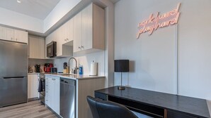 A modern kitchen with stainless steel appliances, a black desk, and a neon sign on the wall. - Executive 2BD+Wifi+Parking+EV (Kitchener)