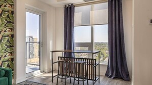 A balcony with a table and chairs, a view of the city, and a green couch. - Executive 2BD+Wifi+Parking+EV (Kitchener)