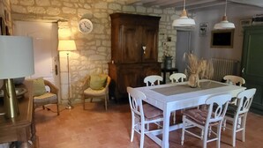 Un coin repas au style rustique, avec un mur en pierre, des poutres en bois au plafond et un sol carrelé.