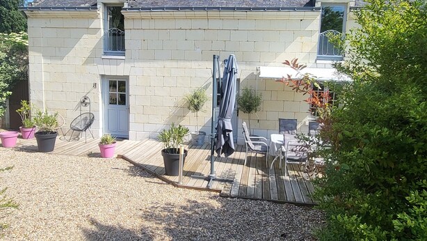 Une maison en pierre avec un toit en tuiles, un petit porche et des plantes en pot.