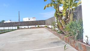 An outdoor parking area with concrete surfaces and a low brick wall.