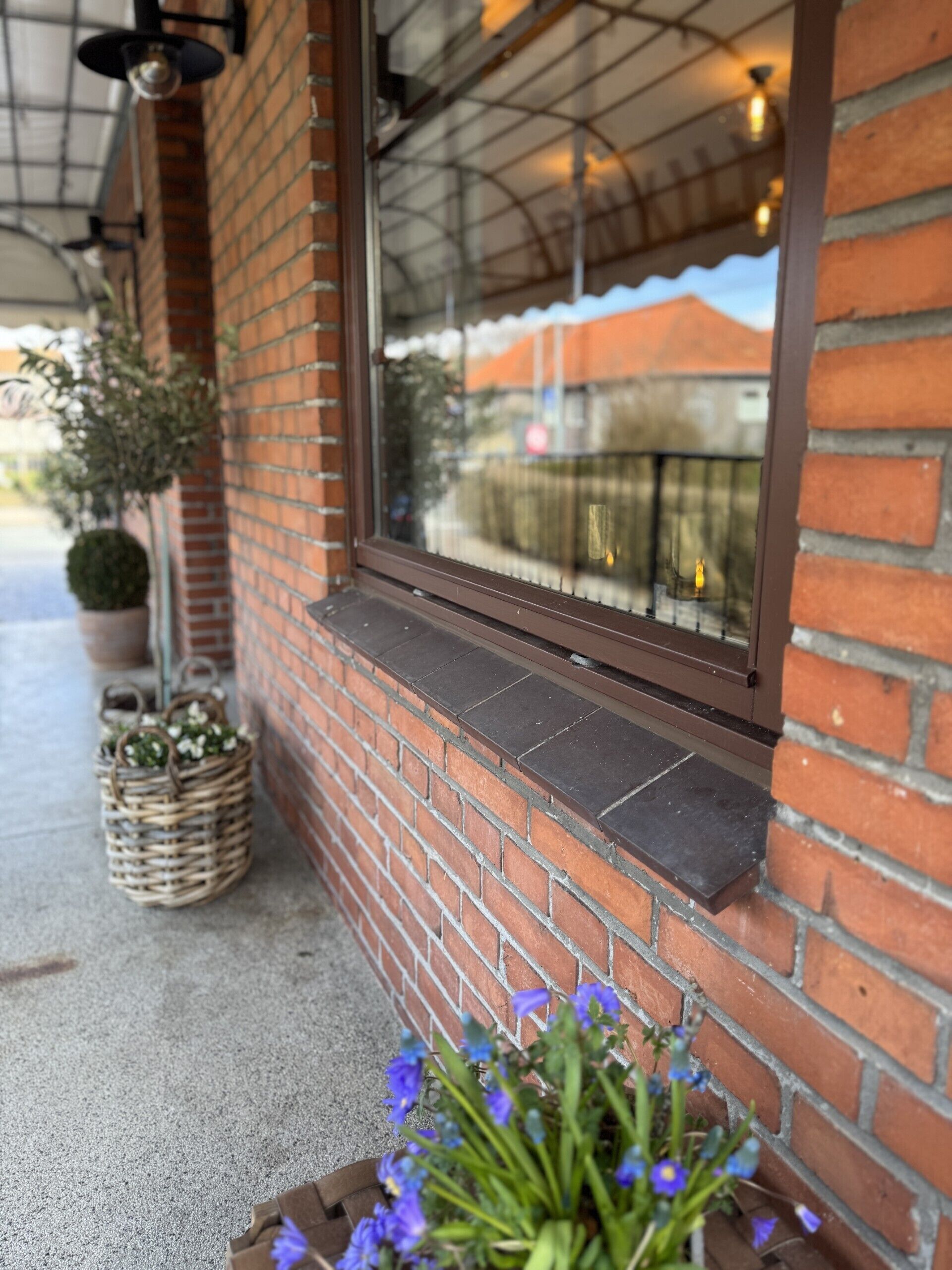 A brick building with a window, a potted plant, and a wicker basket.