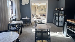 A modern dining area with round tables and black chairs, a glass cabinet with plates, and a decorative wall piece. - Hotel Arnkilhus (Sønderborg)