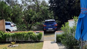 A paved pathway leading to a car parked in a garden with a blue umbrella and a white spherical light fixture. - Rental House St Hilaire De Riez 6/8 people 300 m from the beach, 2 stars (Saint-Hilaire-de-Riez)
