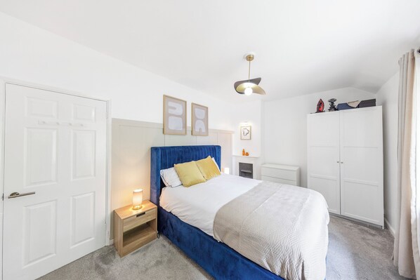 A bedroom with a bed, bedside table, wardrobe, and a ceiling light.