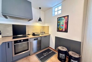 Een kleine keuken met moderne apparatuur, een raam en een deurmat.