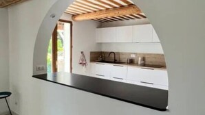Eine moderne Küche mit weißen Schränken, einer schwarzen Arbeitsplatte und einem Holzbalken an der Decke.