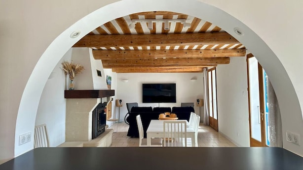 Ein Wohnzimmer mit Kamin, Fernseher und Essbereich mit Tisch und Stühlen.