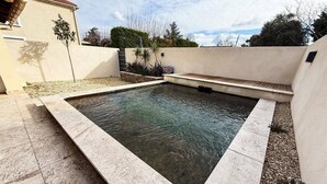 A rectangular swimming pool with a tiled deck, surrounded by a low wall and landscaping. - Villa Keromate, air-conditioned villa with natural pool. (Entraigues-sur-la-Sorgue)