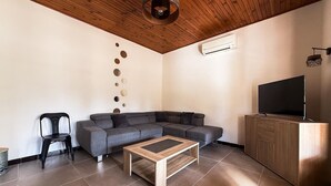 A modern living room with a sectional sofa, a coffee table, a TV stand, and a ceiling light fixture. - Villa Keromate, air-conditioned villa with natural pool. (Entraigues-sur-la-Sorgue)