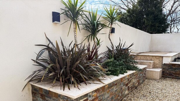 A landscaped garden area with a variety of plants and a stone planter. - Villa Keromate, air-conditioned villa with natural pool. (Entraigues-sur-la-Sorgue)