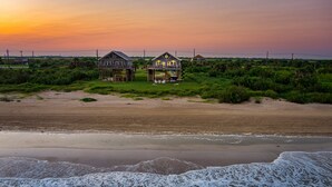Una propiedad frente a la playa con varias casas, una playa arenosa y vista al océano.