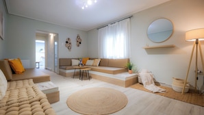 A modern living room with a sofa, a round rug, a coffee table, and a lamp. - Vayas Residences Legacy (Trikala)