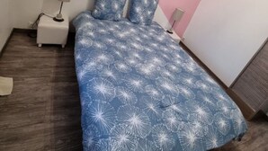 Ett sovrum med en säng, två sängbord, ett litet bord, en rosa accentvägg och en inramad tavla på väggen.