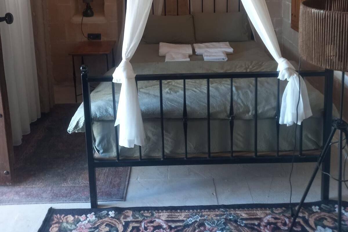 Une chambre avec un lit à baldaquin, une table de chevet, une lampe et un miroir.