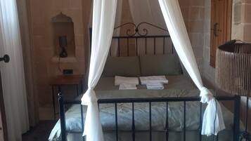 Una habitación con una cama con dosel, una mesita de noche, una lámpara y un espejo.