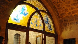 Una habitación con paredes de piedra, techos abovedados y una ventana de vitral.