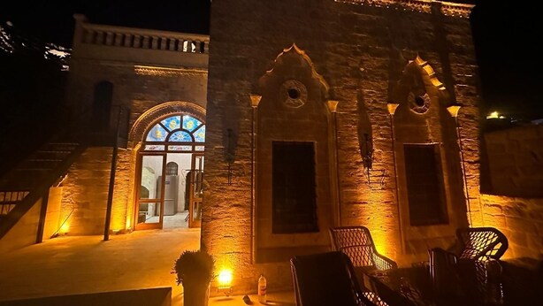 Un edificio de piedra con arcos y una escalera que conduce a una puerta con un vitral.
