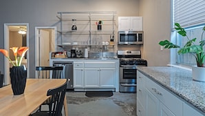 A modern kitchen with white cabinets, stainless steel appliances, and a black countertop.
