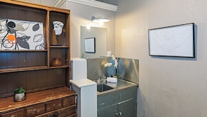 A bathroom with a wooden vanity, a sink, a mirror, and a framed artwork on the wall.