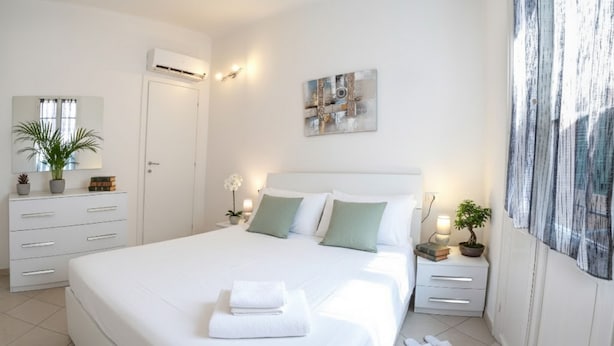 Un dormitorio moderno con una cama grande, mesitas de noche, un espejo y una planta en maceta.