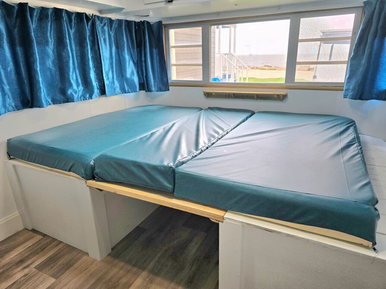 Una camera compatta con un letto singolo, una finestra con tende e vista all'esterno.