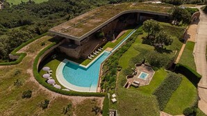 Oversigtsbillede af et resort med en stor pool, en overdækket bro og velplejede haver.