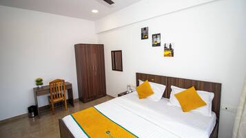 Ein Hotelzimmer mit Bett, Holzschrank, Schreibtisch, Stuhl und einem Bild an der Wand.