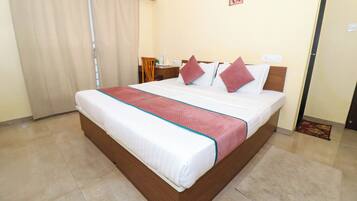 A neatly made bed with a red and white bedspread, a wooden headboard, and two red pillows.
