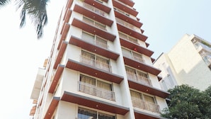 Un immeuble à plusieurs étages, doté de balcons, de grandes fenêtres et d’une base en béton.