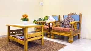 Un salon avec une table en bois, deux chaises en bois, une plante en pot et un tableau encadré accroché au mur.
