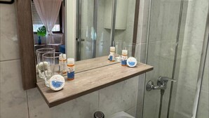 A bathroom with a wooden shelf holding various toiletries and a mirror. - Hostal Barco da Vella (Muxía)