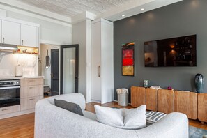 A modern living room with a grey sofa, wooden sideboard, and a flat-screen TV mounted on the wall. - Gateway Inn:  Harmony Loft 2BRM (Stratford)