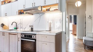 A modern kitchen with white cabinets, a built-in oven, and a marble backsplash.
