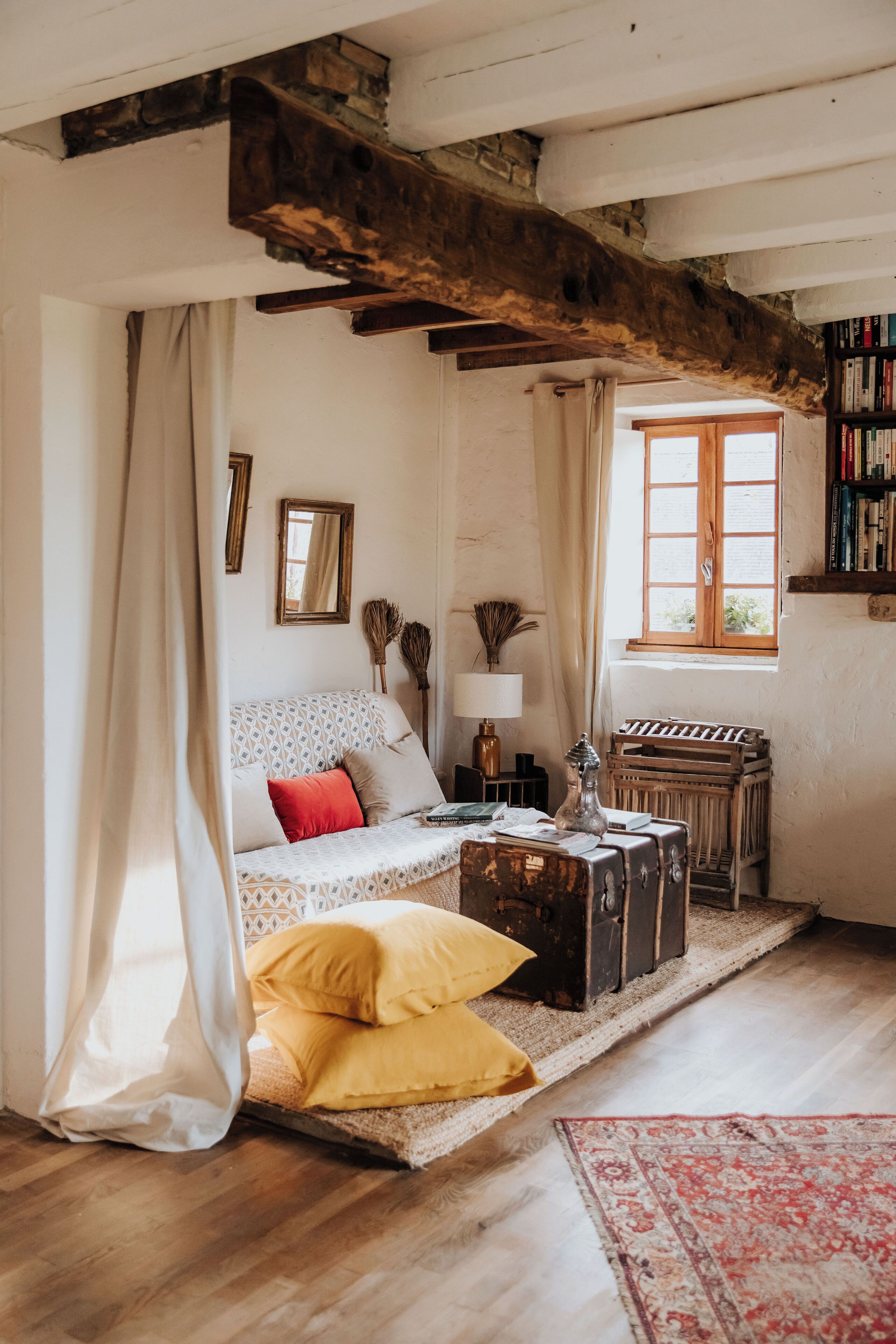 A cozy room with a patterned sofa, a wooden bench, and a vintage suitcase.