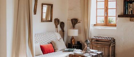 A cozy room with a patterned sofa, a wooden bench, and a vintage suitcase.