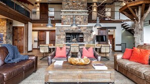 A spacious living area with leather sofas, a central coffee table, and a stone fireplace. - The Elmwood Wellness Estate (Dundas)