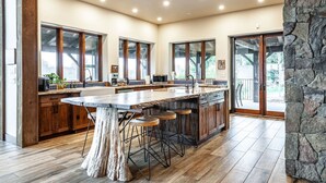 A spacious kitchen with a large island, wooden cabinets, and a stone accent wall. - The Elmwood Wellness Estate (Dundas)