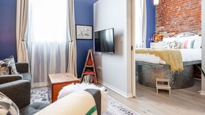 Une chambre à coucher moderne avec un mur en briques, un lit, une télévision et une bibliothèque.