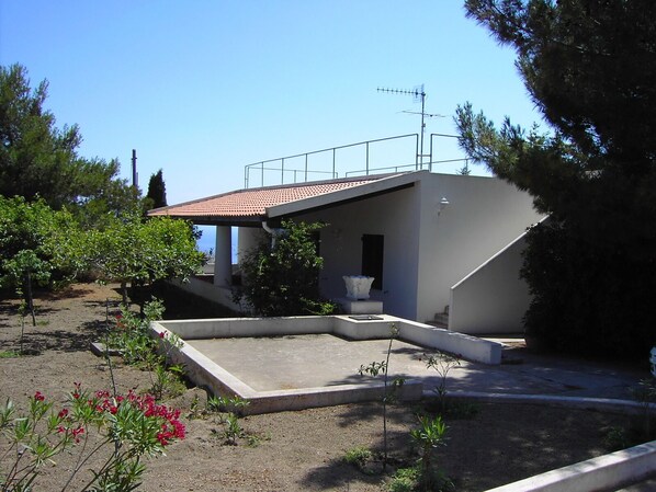 A modern house with a sloped roof, a small porch, and a concrete patio area.