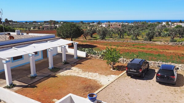 Una propiedad residencial con un porche cubierto, un toldo para el coche y vistas al mar.