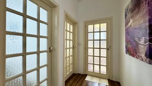 A hallway with three white-framed doors, wooden flooring, and a large abstract painting on the wall. - Villetta Certosina 2 (Racale)