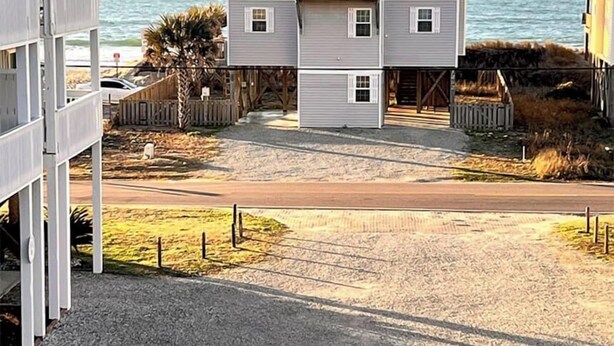 A two-story building with a balcony on the second floor, located near a beach with a clear view of the ocean. - Ocean Heir -The Water is Calling (North Topsail Beach)
