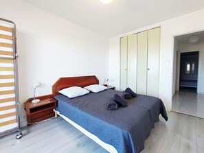 A bedroom with a bed, nightstand, lamp, and wardrobe.