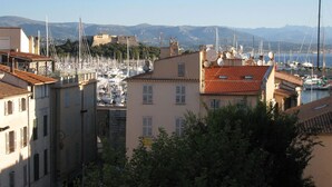 A marina with boats, a castle in the background, and buildings with red-tiled roofs.