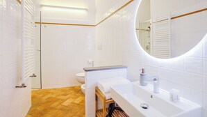 Une salle de bain moderne avec des carreaux blancs, un meuble-lavabo en bois, un grand miroir et un espace douche.