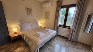 Une chambre à coucher avec un lit, une table de chevet, une fenêtre avec des rideaux et des œuvres d’art murales.